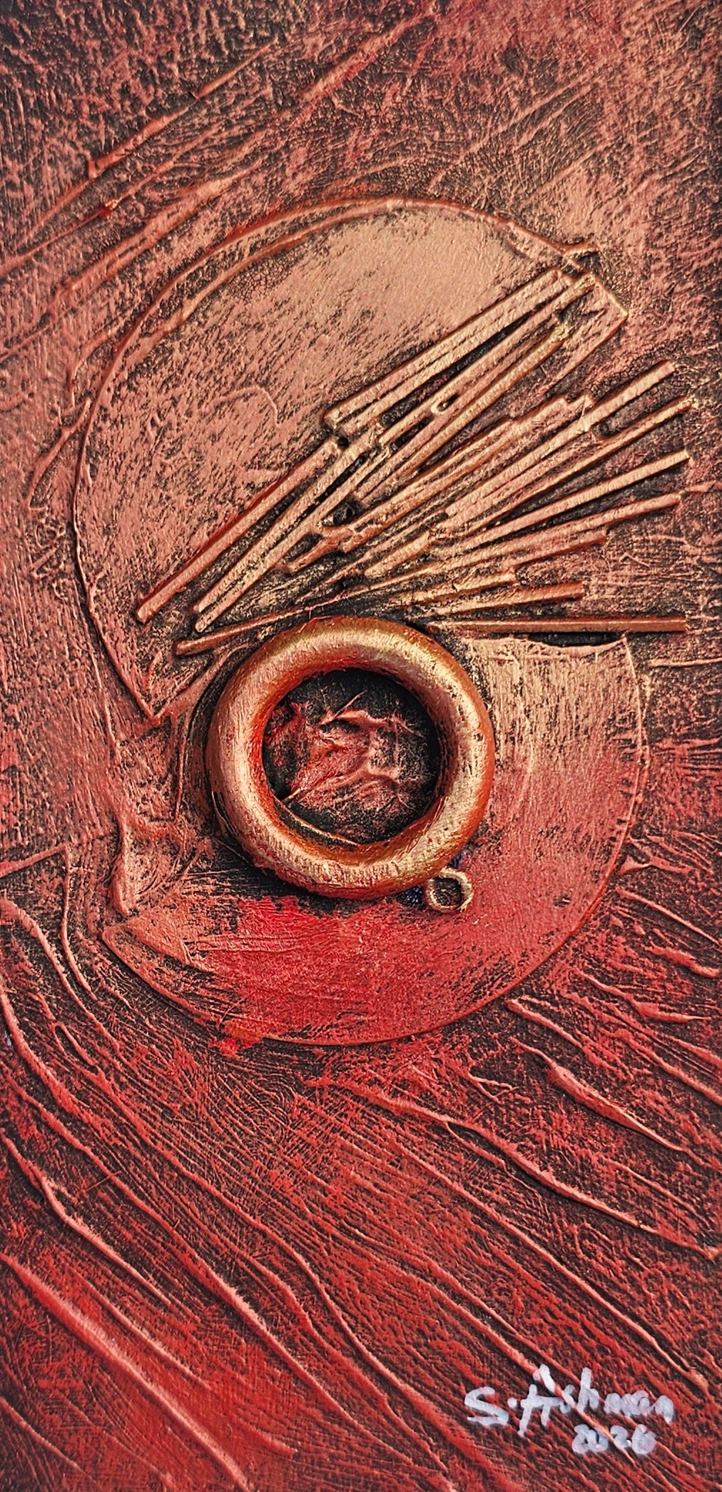 An abstract textured painting featuring a central circular medallion with radiating metallic-looking lines, set against a rich red and brown background with visible brushstrokes and a white artist signature in the lower right.
